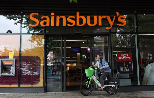 a woman riding a bike in front of sainsbury 's