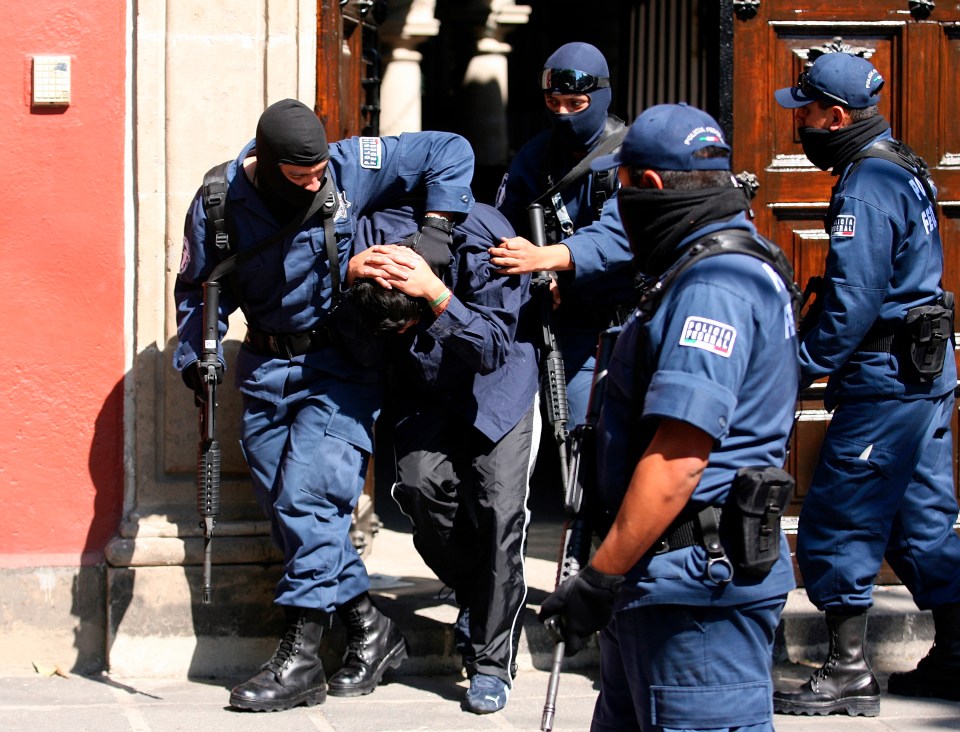 Members of Mexico’s Federal Investigative Agency’s escort a detained man out of a mansion in Mexico City in 2008