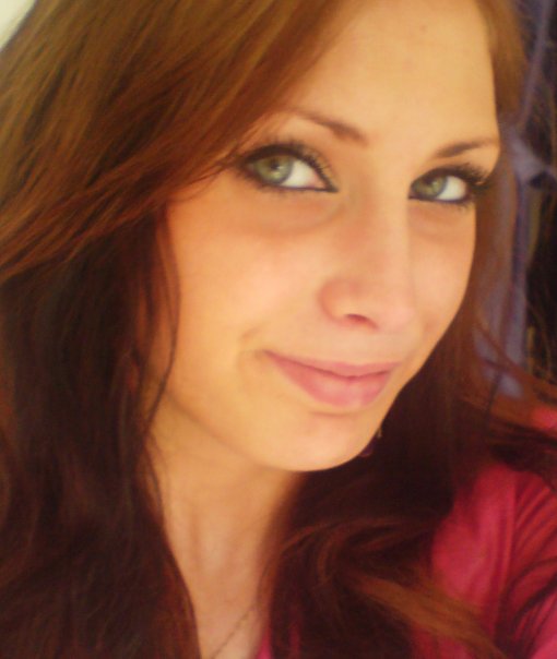 a close up of a woman 's face with brown hair and green eyes