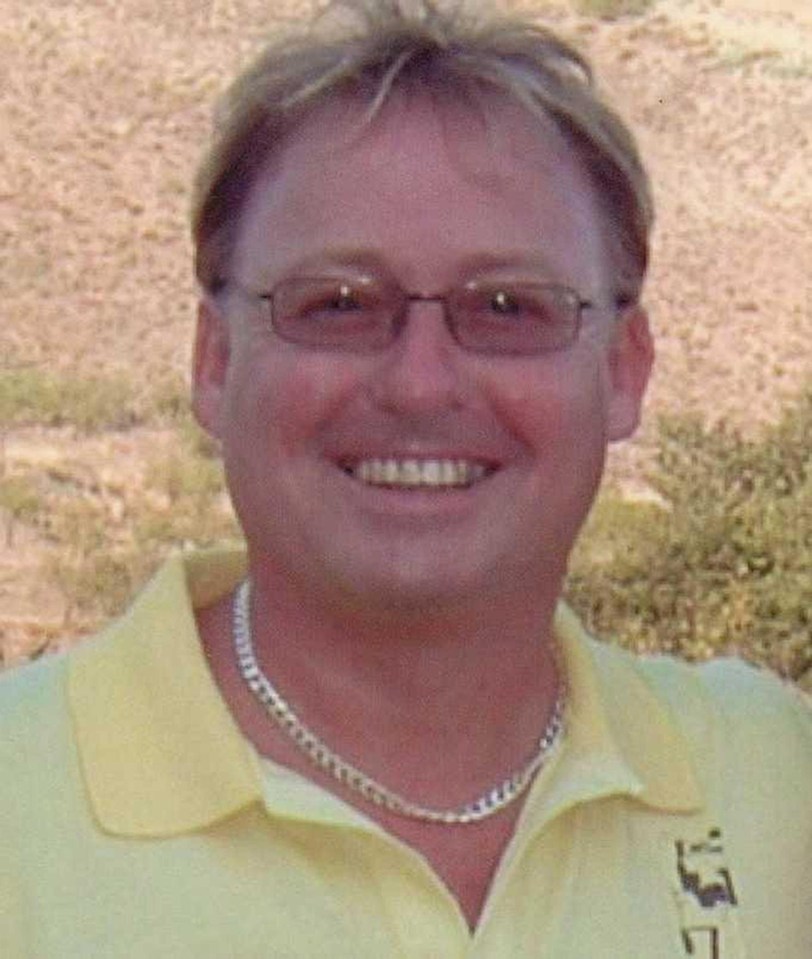 a man wearing glasses and a yellow shirt is smiling for the camera .