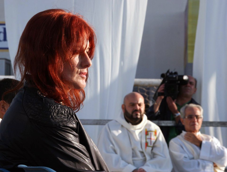 a woman with red hair sits in front of a man in a white robe with the letter f on it