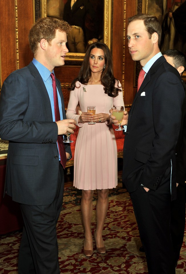 a woman in a pink dress stands between two men in suits