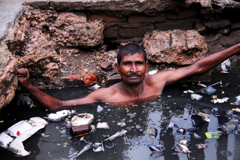 a man is swimming in a body of water surrounded by trash