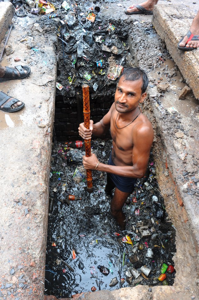 a shirtless man is standing in a hole in the ground holding a stick