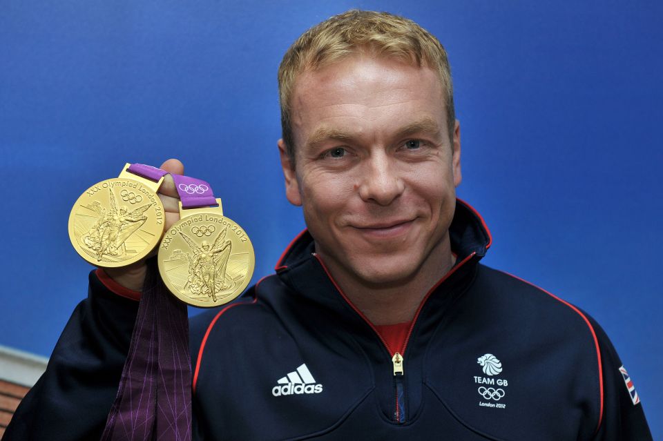 a man wearing an adidas jacket holds up two gold medals