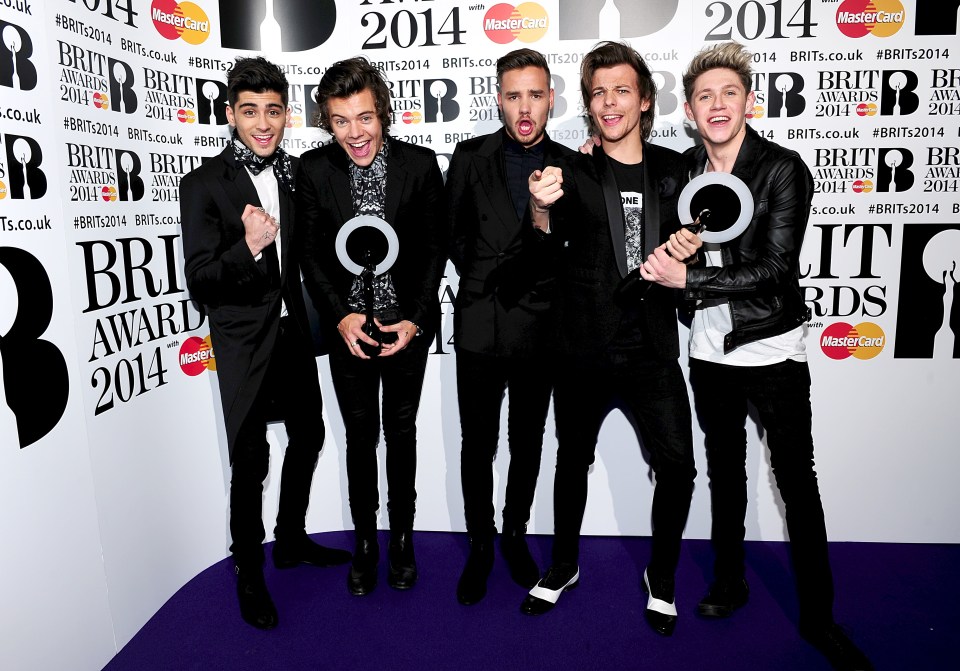 a group of young men standing in front of a wall that says brit awards 2014