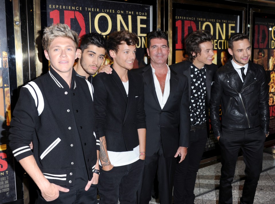 a group of men standing in front of a sign that says one direction