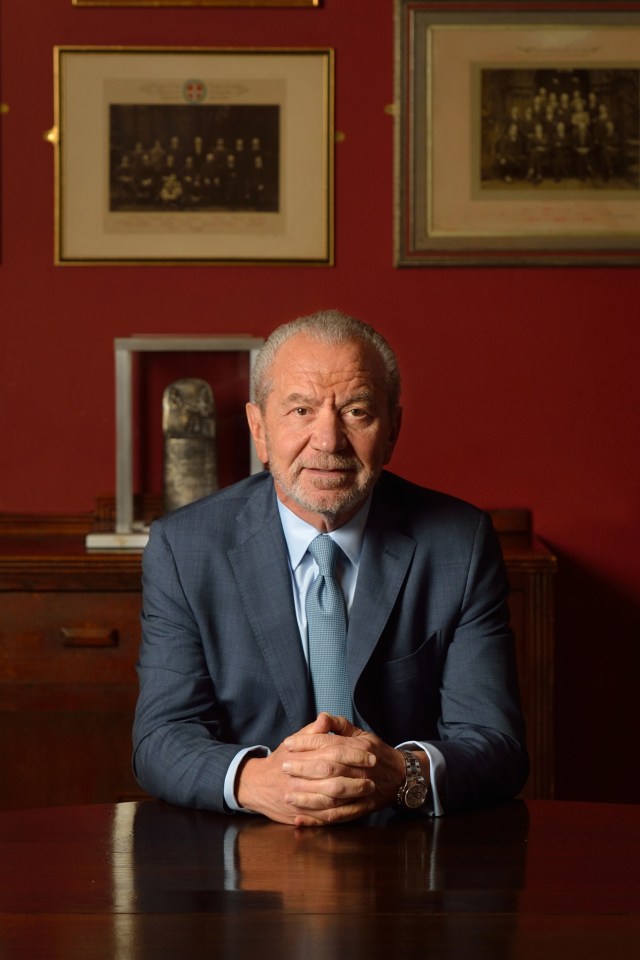 a man in a suit and tie sits at a desk with his hands folded