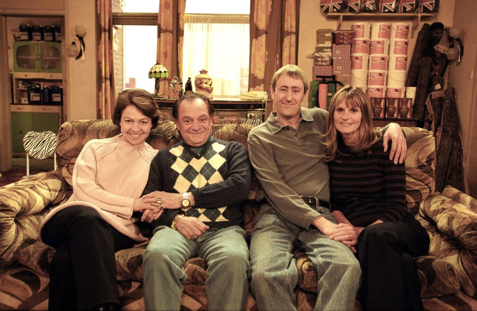 a family posing for a picture on a couch in front of a wall with british flags on it