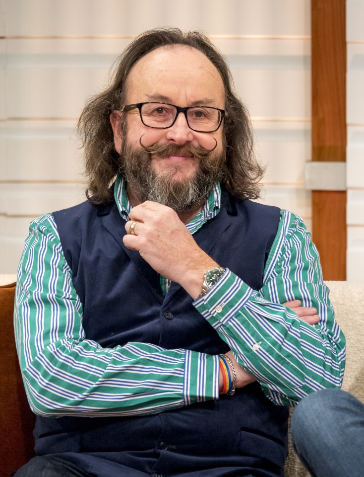 a man with glasses and a beard wears a green and blue striped shirt