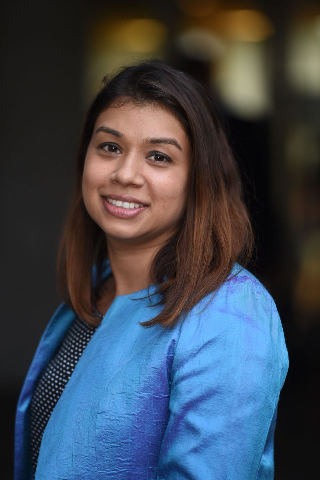 a woman in a blue jacket smiles for the camera