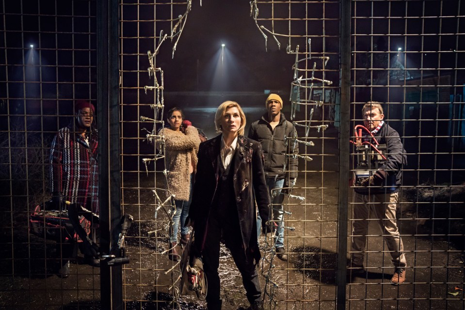 a group of people standing in front of a fence with a broken window