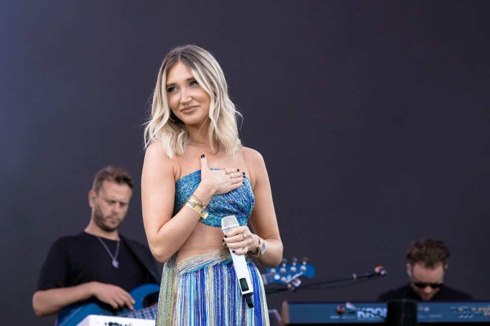 a woman singing into a microphone in front of a keyboard that says krono