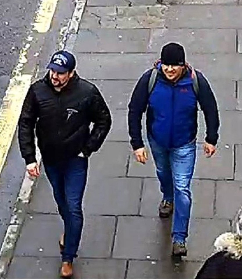 two men are walking down a sidewalk wearing hats and jackets .