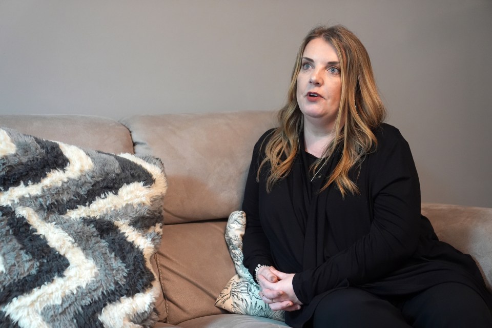 a woman sits on a couch with her hands folded