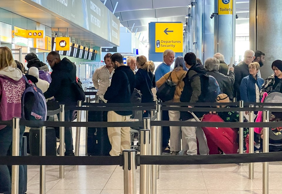 a large group of people are waiting in line at departures security