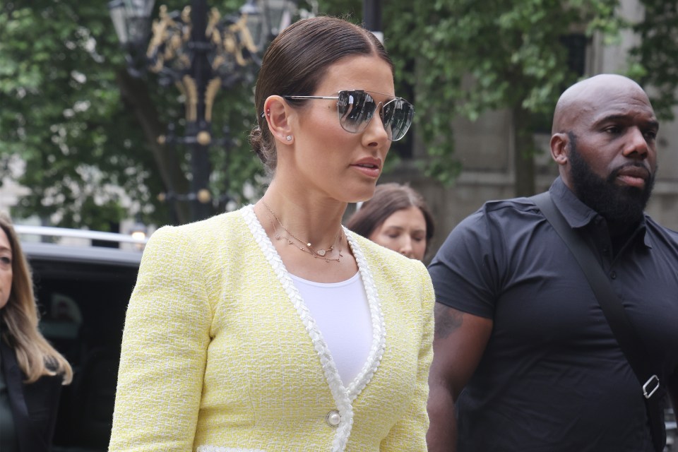 a woman wearing sunglasses and a yellow jacket walks down the street