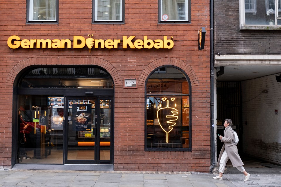 a woman walks past a german dener kebab store