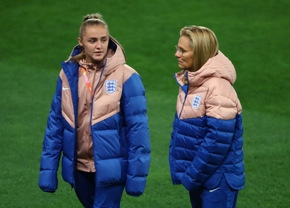 two women standing on a field wearing nike jackets