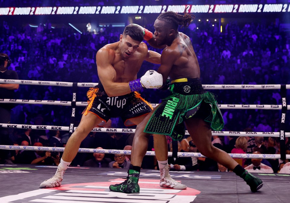 a boxer wearing green shorts that say prime is fighting another boxer