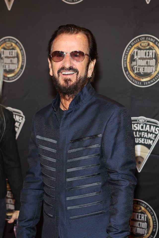 a man wearing sunglasses stands in front of a sign that says concert induction ceremony