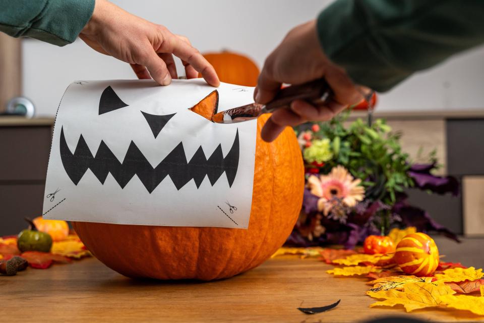 a person is carving a pumpkin with a drawing of a face on it