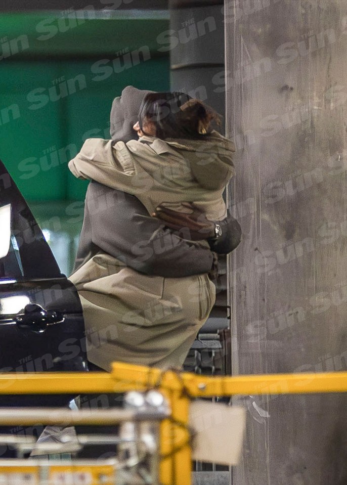 a couple hugging in front of a wall that has the sun written on it