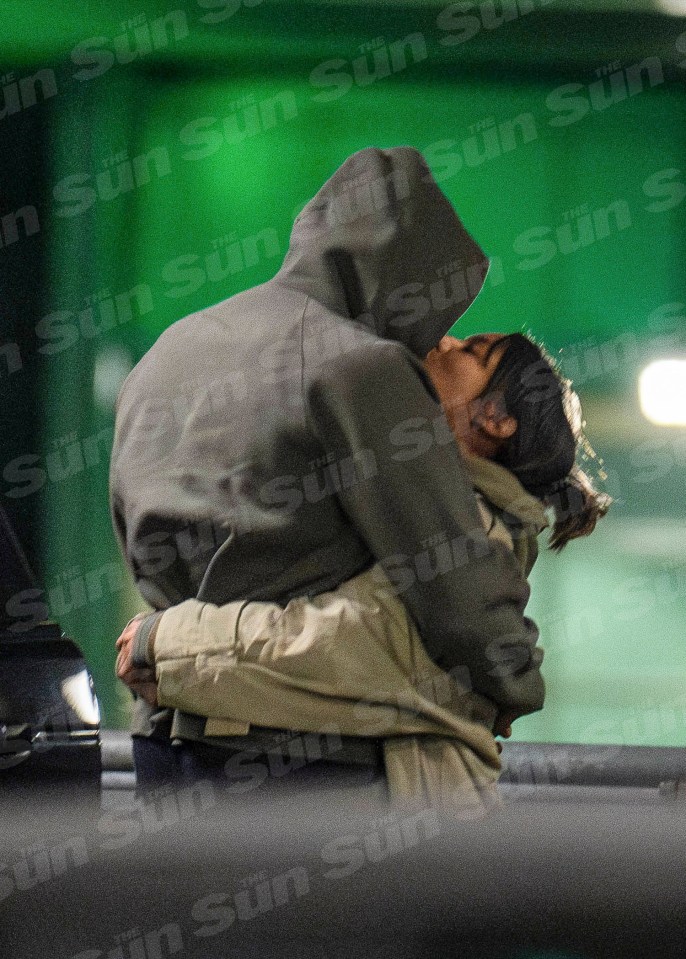 a man in a hoodie kisses a woman in front of the sun newspaper