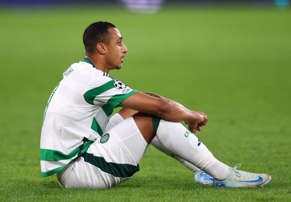 a soccer player sits on the grass with his legs crossed