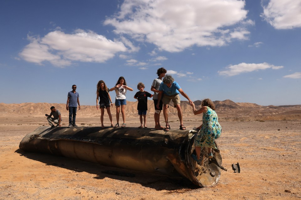 a group of people standing around a large metal object in the desert