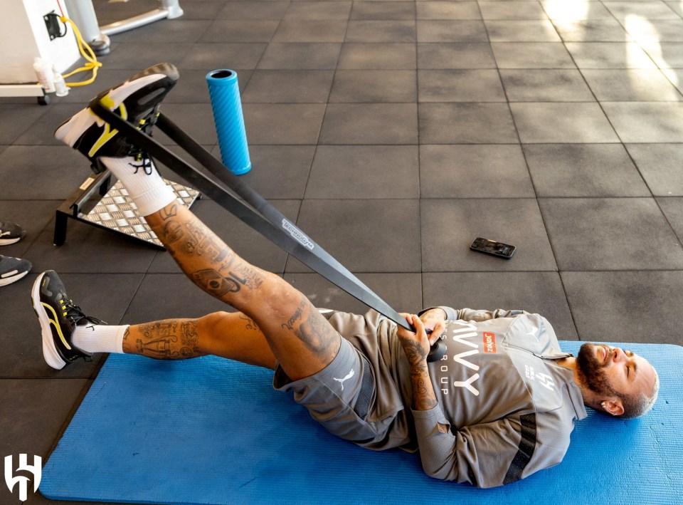 a man is laying on a blue mat with a resistance band around his leg