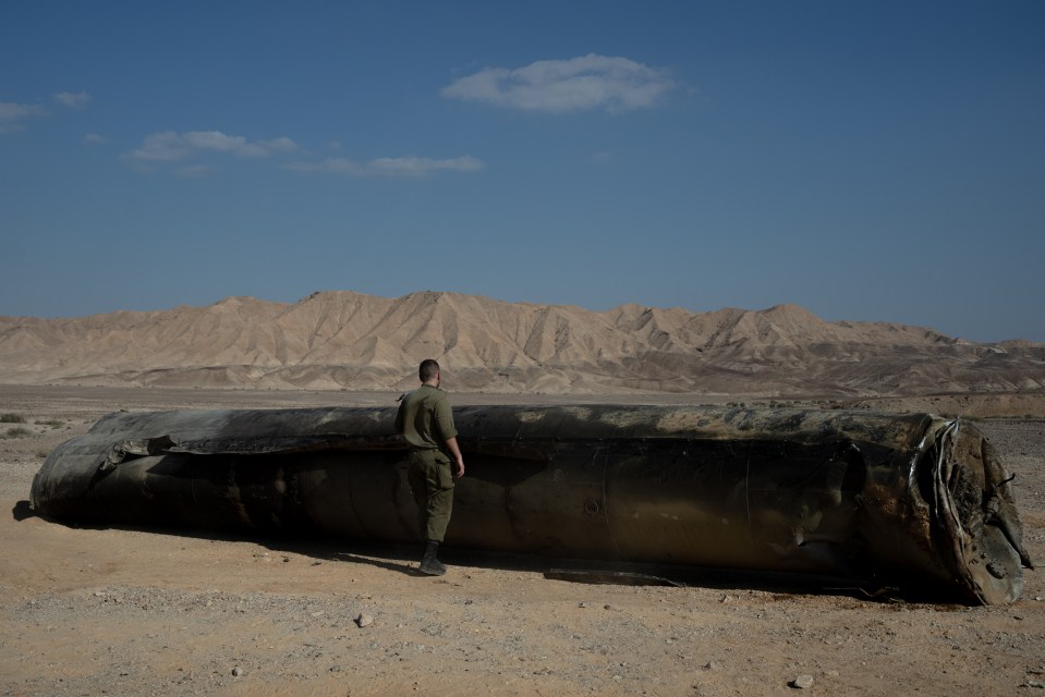 A soldier inspects the leftover carcass of an Iranian missile in Israel