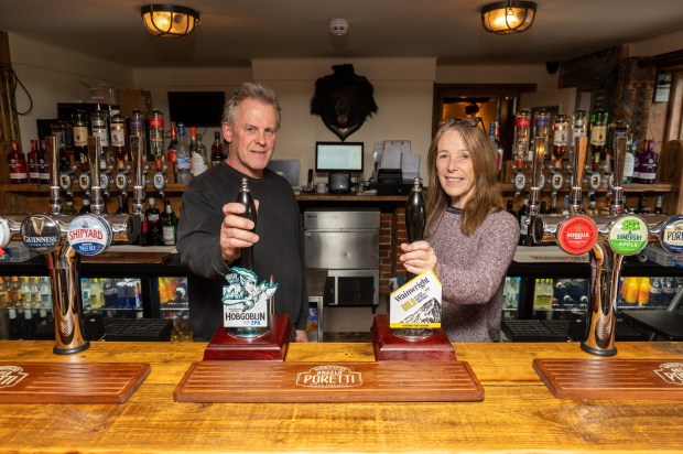 a man and woman holding a bottle of hobgoblin beer