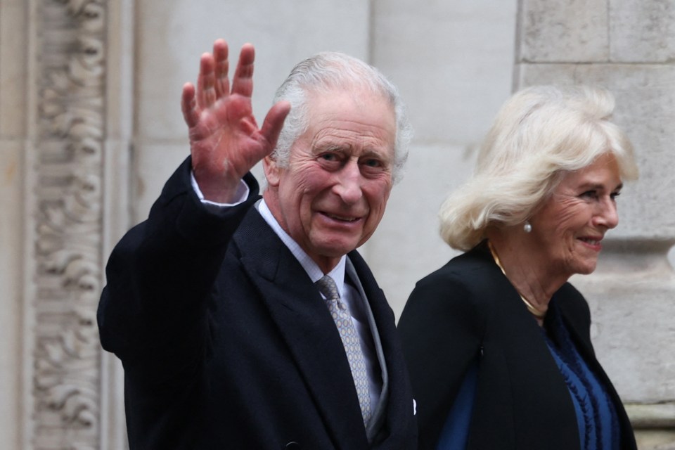 a man in a suit and tie is waving while standing next to a woman