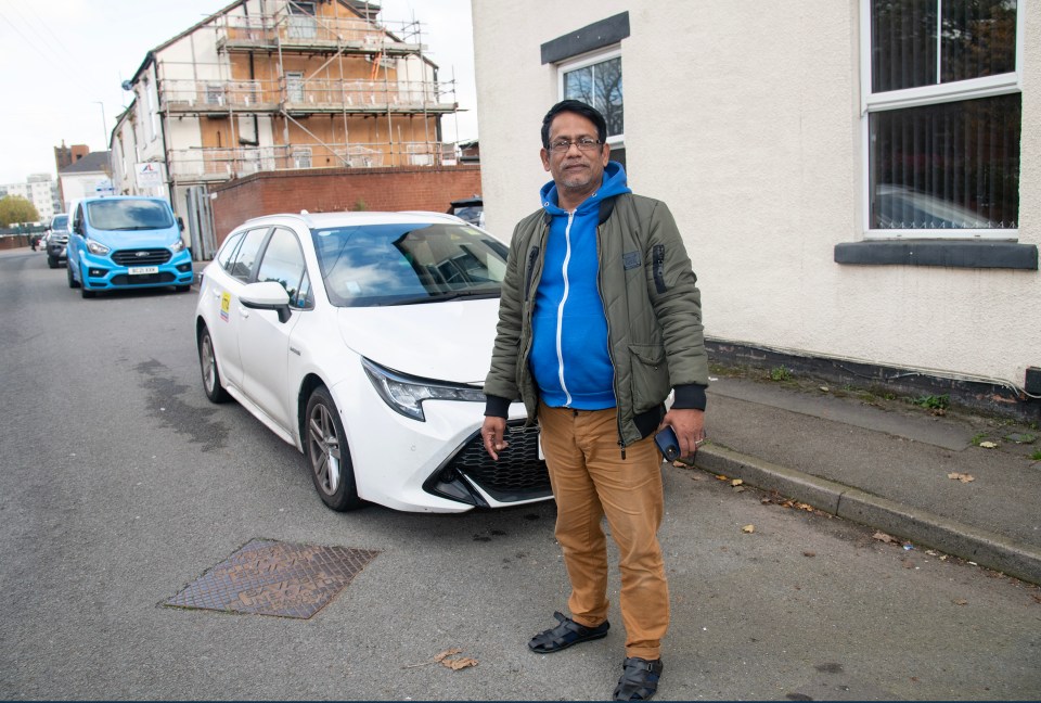 a man in a green jacket stands in front of a white car