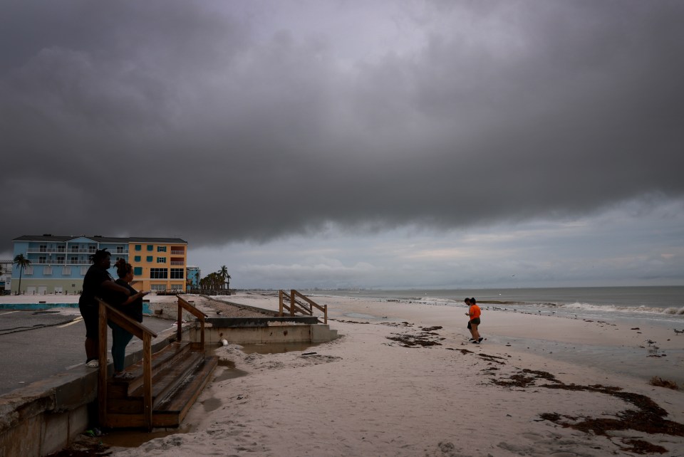 People visit the beach as storm clouds hang pass overhead before Hurricane Milton’s arrival