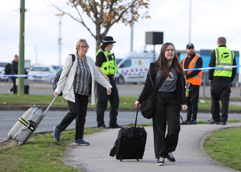 a woman wearing an adidas shirt is pulling a suitcase