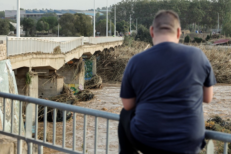 A resident looks on at a damaged bridge in flood-hit Ribarroja del Turia