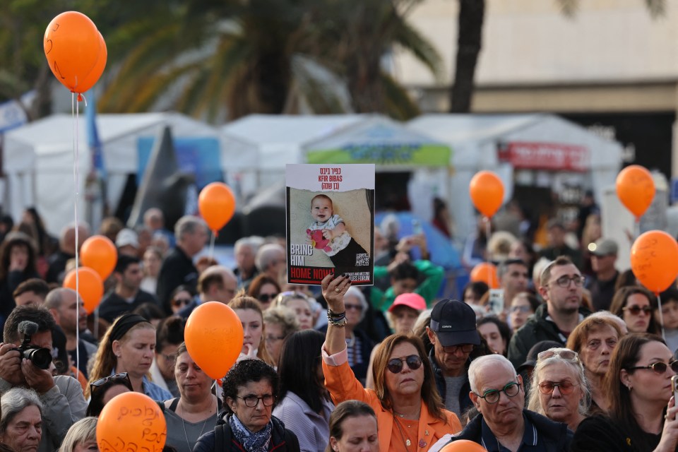 A woman holds a picture of hostage Kfir at a protest in Tel Aviv on what would have been his first birthday in January