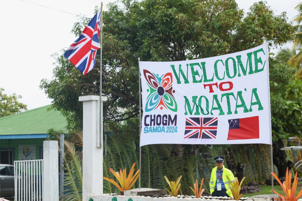 A police officer stands guard next to a welcome sign at Moata'a Village