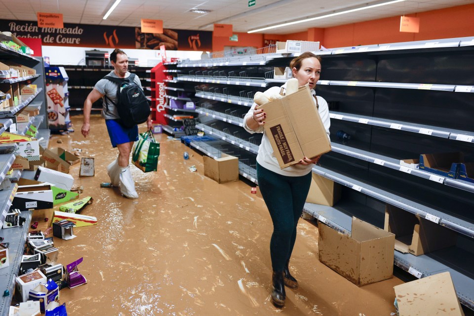 Residents collect items from a supermarket covered in mud