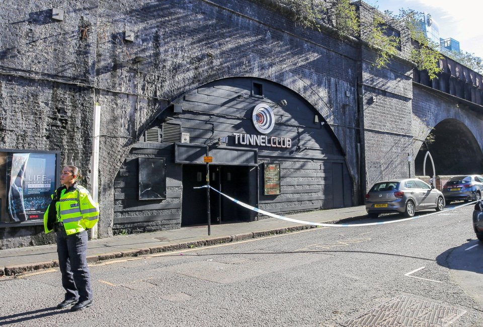 a man in a yellow vest stands in front of a tunnel club