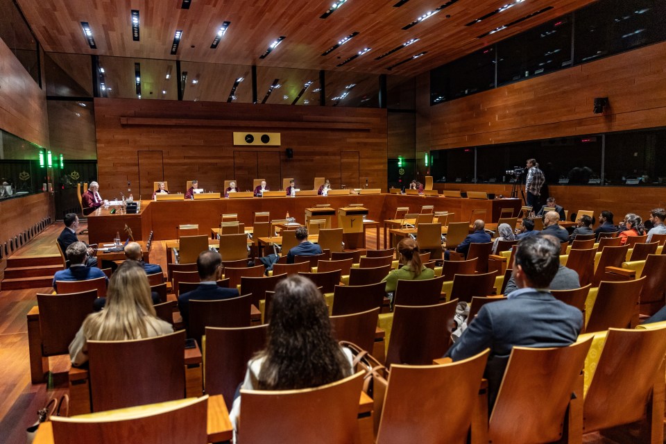 a group of people sit in a large auditorium watching a presentation