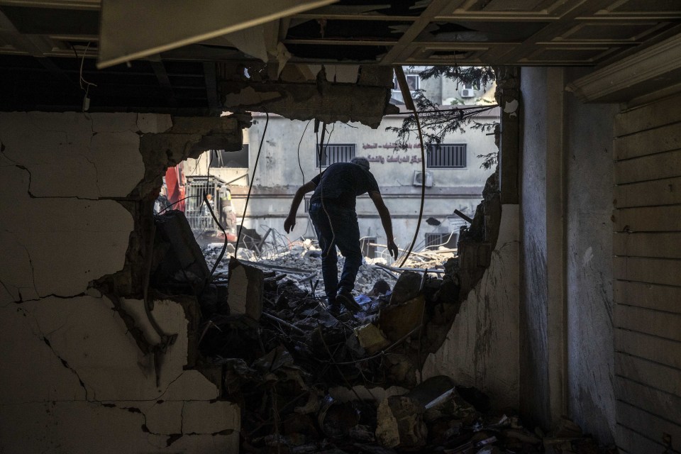 A man climbs through rubble in Lebanon after an Israeli strike