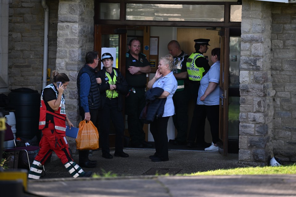 a group of people standing outside of a building with one wearing a shirt that says ' ambulance ' on it