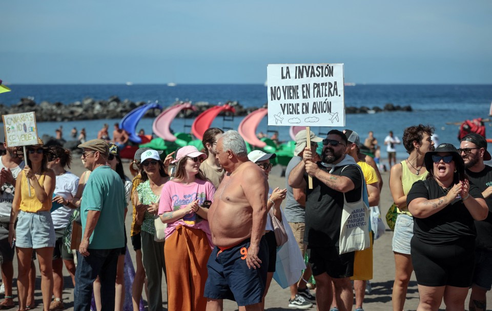 a man holding a sign that says la invasion no viene en patera viene en avion