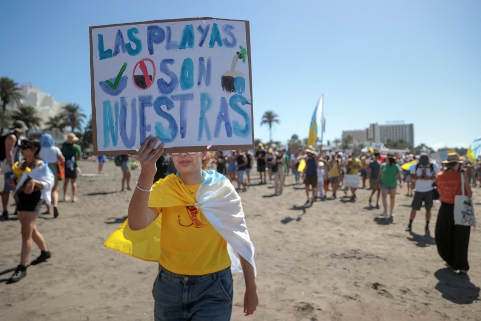 a person holding a sign that says las playas