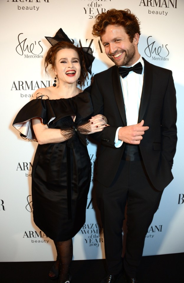 a woman in a black dress smiles next to a man in a tuxedo