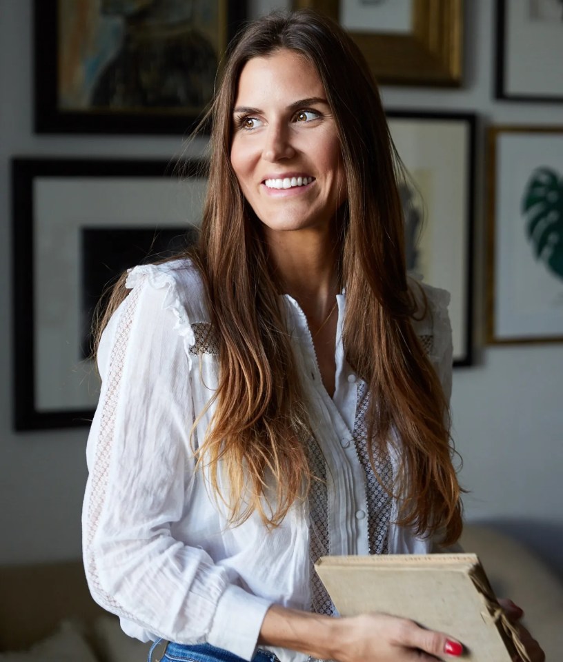 a woman in a white shirt is smiling and holding a book