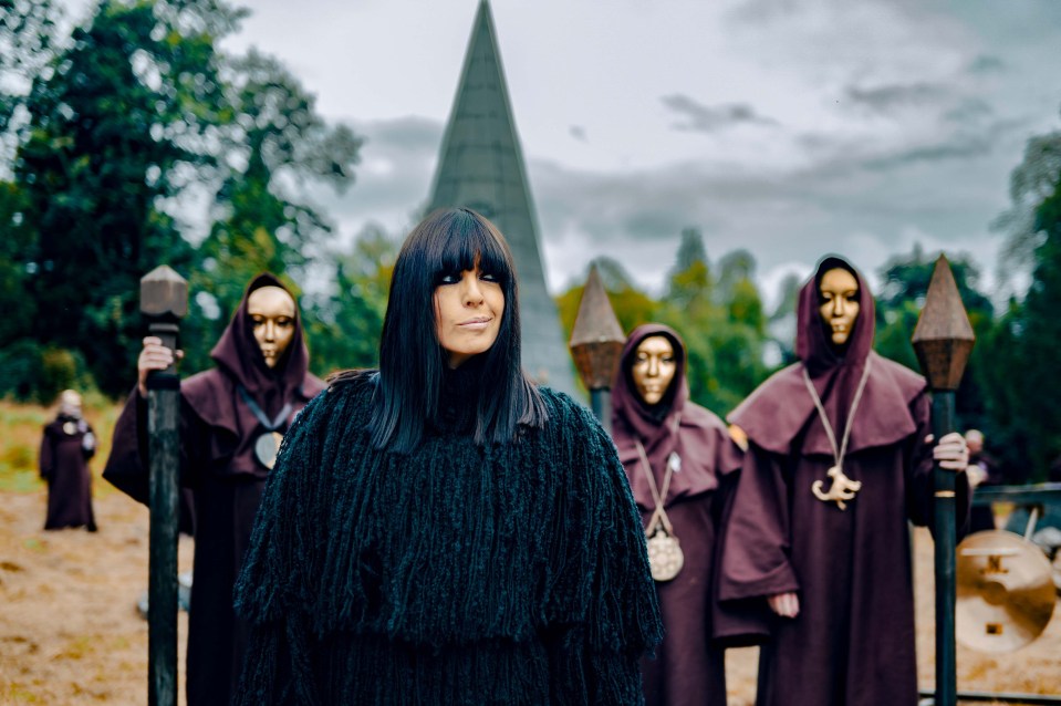 a woman in a black sweater stands in front of a pyramid